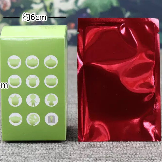 Green box with white icons and red foil bag on a textured surface